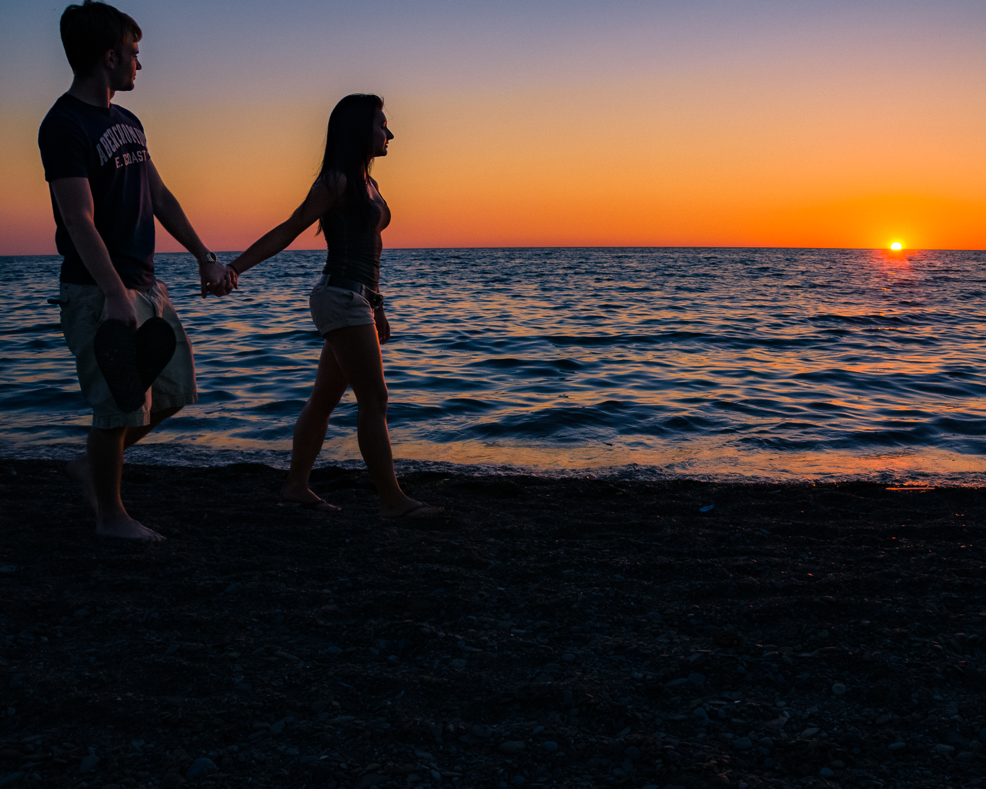 Couple waking on the beach at sunset